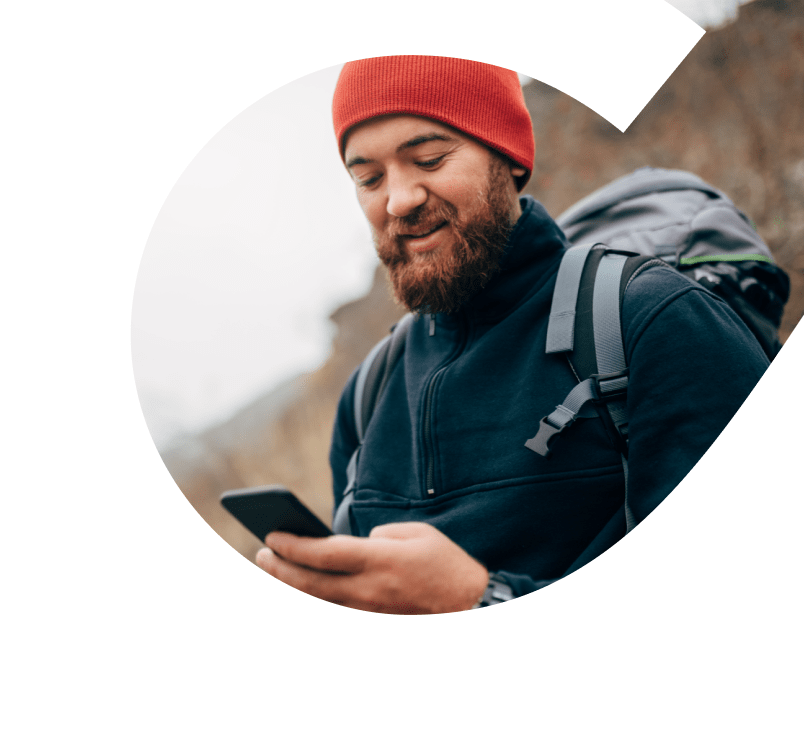 young man hiking. He is wearing a red tuque and holding a phone